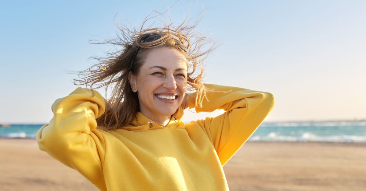 Woman on the beach smiling and looking into the sun